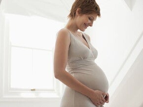 Femme enceinte tenant tendrement son ventre, illustrant l’importance de l’acide folique et des vitamines pendant la grossesse