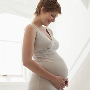 Pregnant woman cradling her belly, representing the importance of folate and vitamins during pregnancy